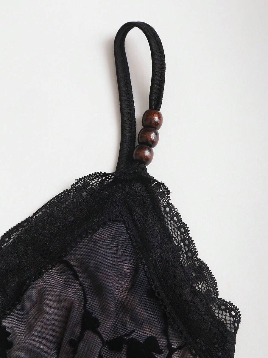Women's black spaghetti strap tank top featuring contrast lace details, asymmetric ruffle hem, and slim fit design.