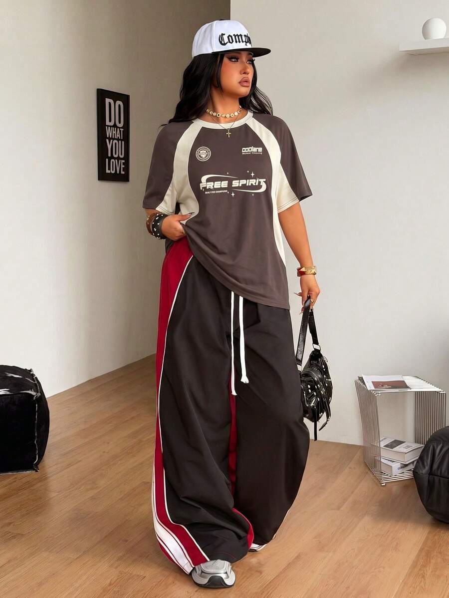 Unisex plus size oversized jersey t-shirt in brown featuring a round neck, short raglan sleeves with contrast binding, and a front letter graphic print.