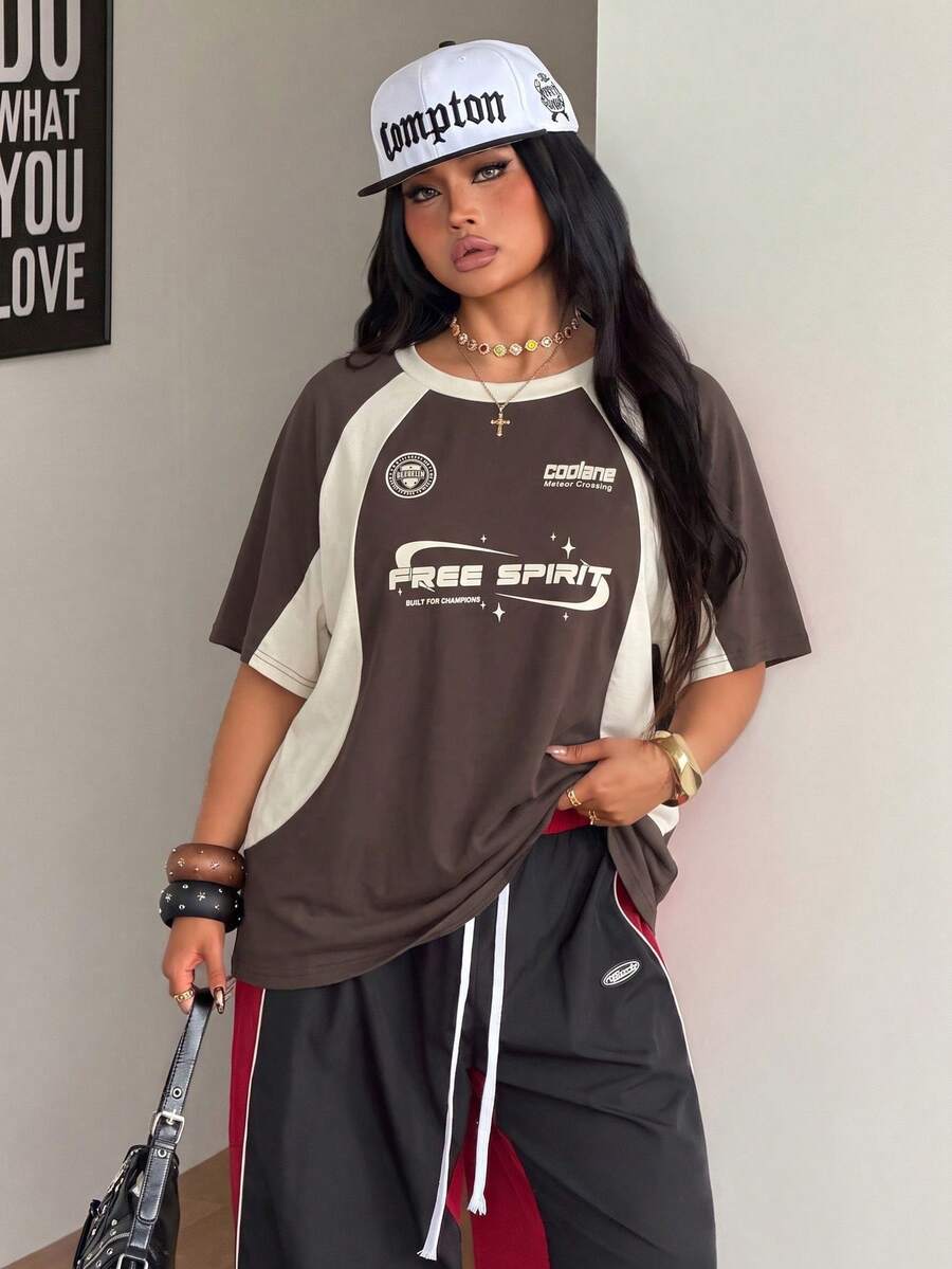 Unisex plus size oversized jersey t-shirt in brown featuring a round neck, short raglan sleeves with contrast binding, and a front letter graphic print.