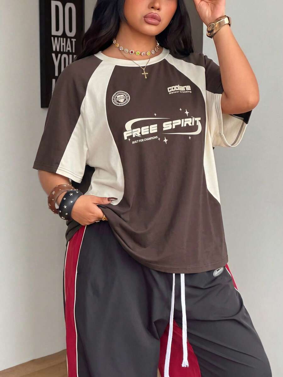 Unisex plus size oversized jersey t-shirt in brown featuring a round neck, short raglan sleeves with contrast binding, and a front letter graphic print.