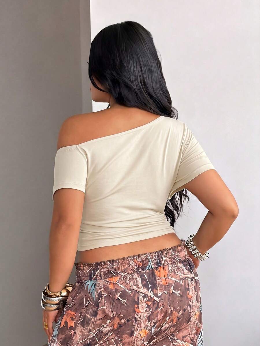 Plus size women's one shoulder short sleeve crop top with grommet eyelet detail in high stretch fabric.