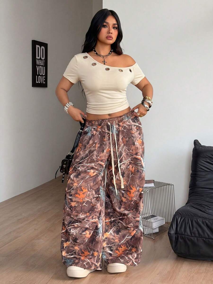Plus size women's one shoulder short sleeve crop top with grommet eyelet detail in high stretch fabric.
