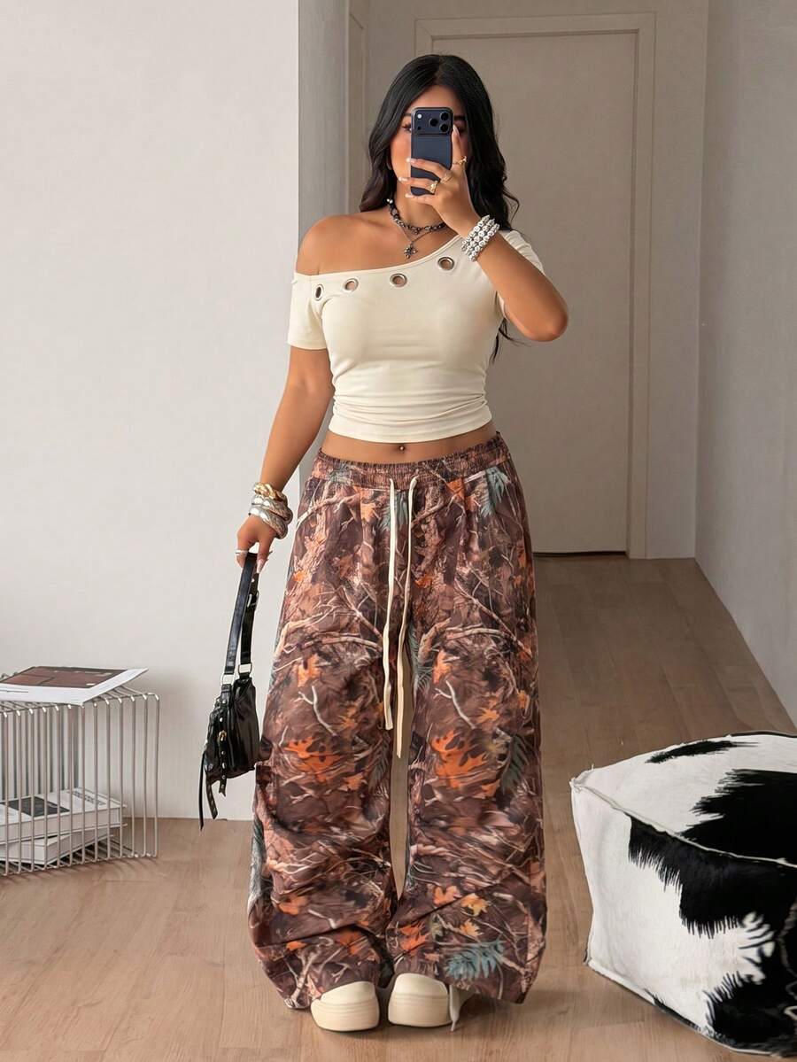 Plus size women's one shoulder short sleeve crop top with grommet eyelet detail in high stretch fabric.