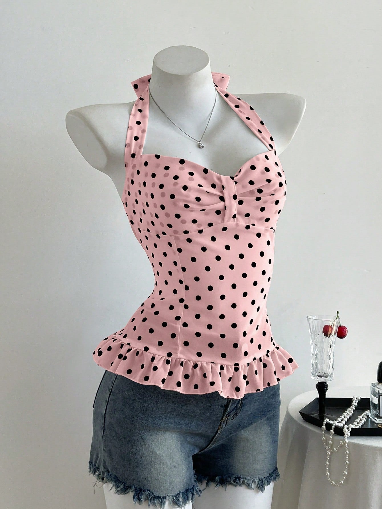Women's polka dot halter camisole with bow bust detail, ruched and shirred design, slim crop fit, and flared ruffle hem.