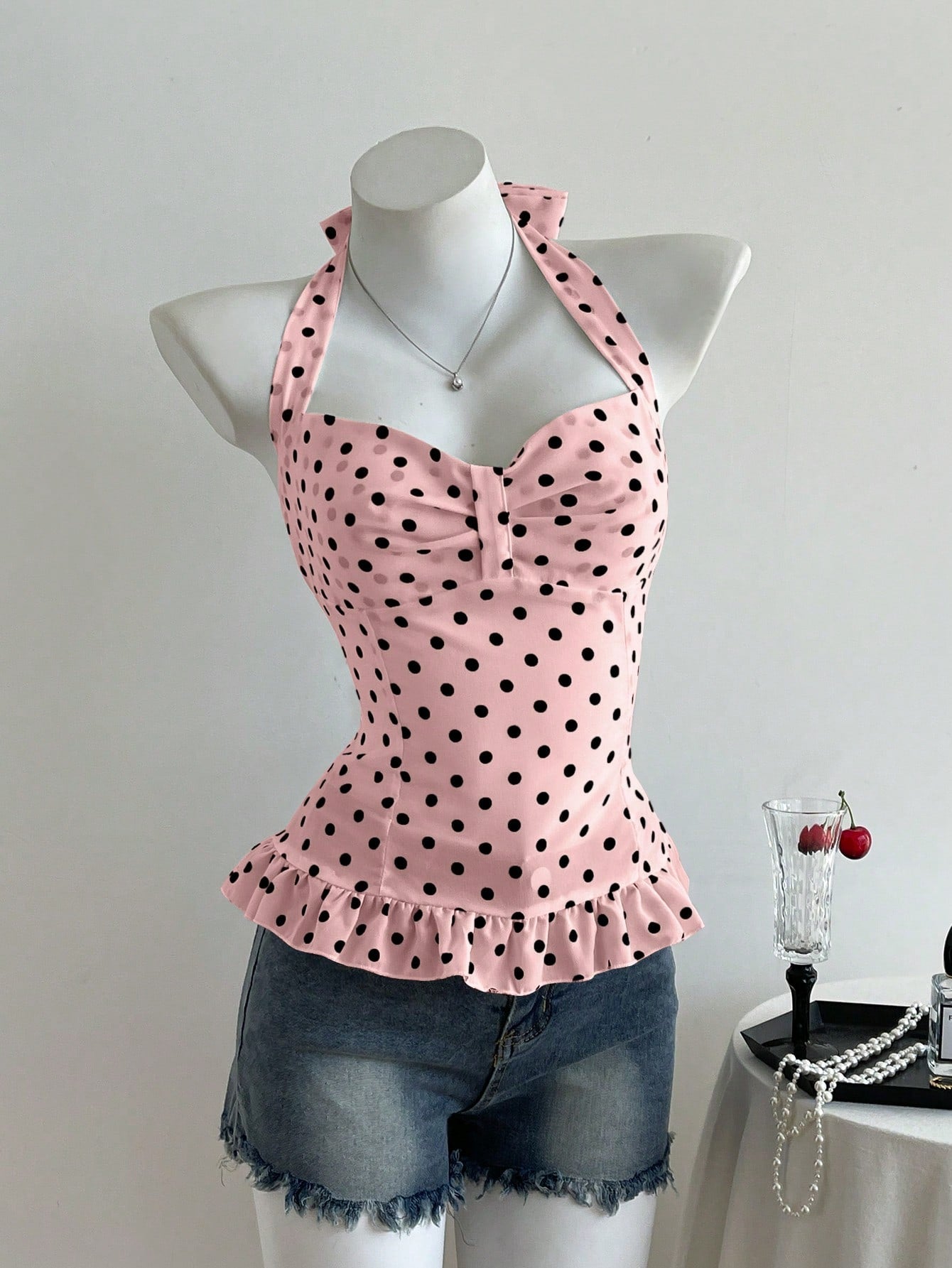 Women's polka dot halter camisole with bow bust detail, ruched and shirred design, slim crop fit, and flared ruffle hem.