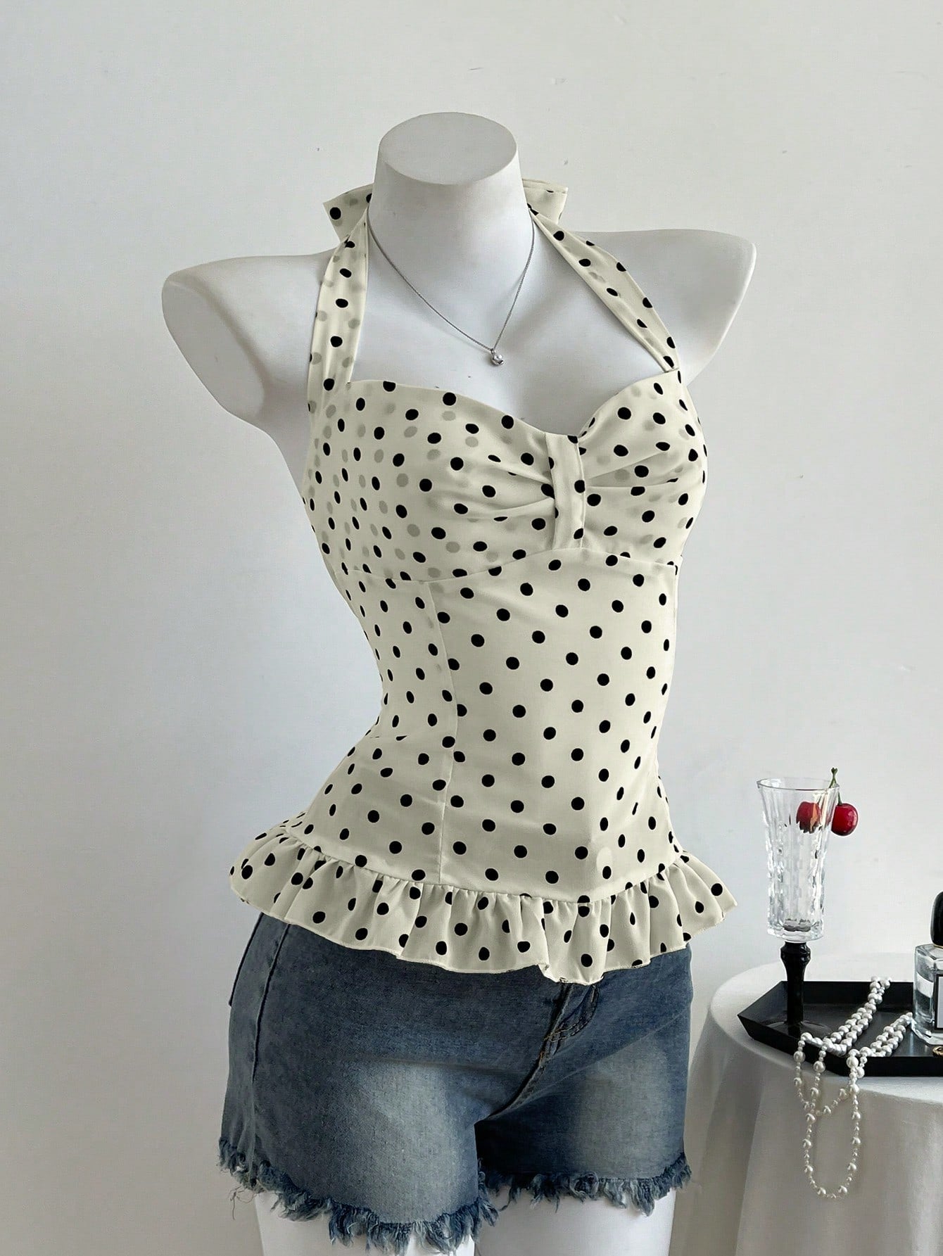 Women's polka dot halter camisole with bow bust detail, ruched and shirred design, slim crop fit, and flared ruffle hem.