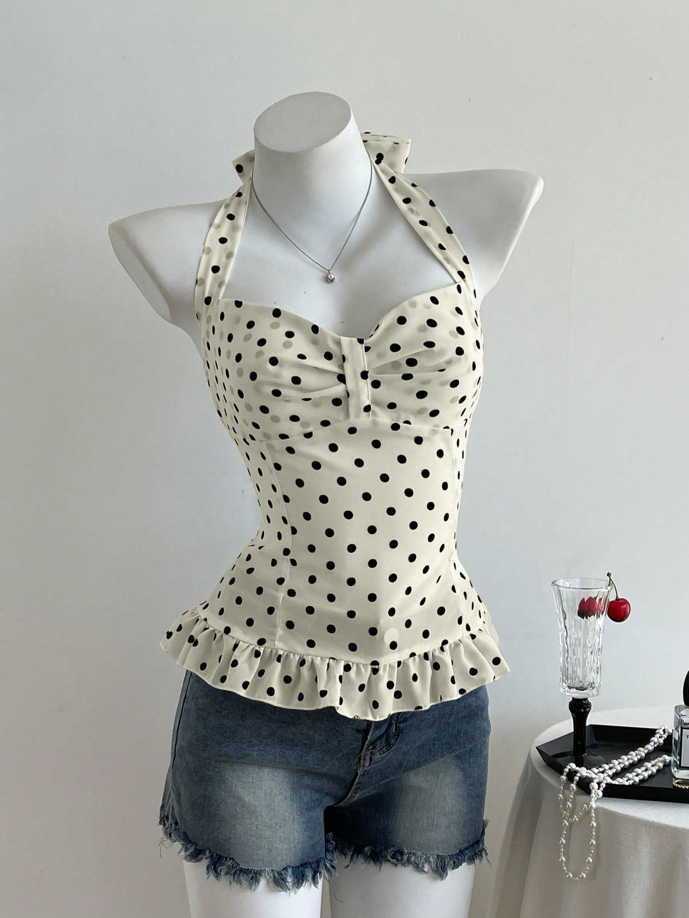 Women's polka dot halter camisole with bow bust detail, ruched and shirred design, slim crop fit, and flared ruffle hem.