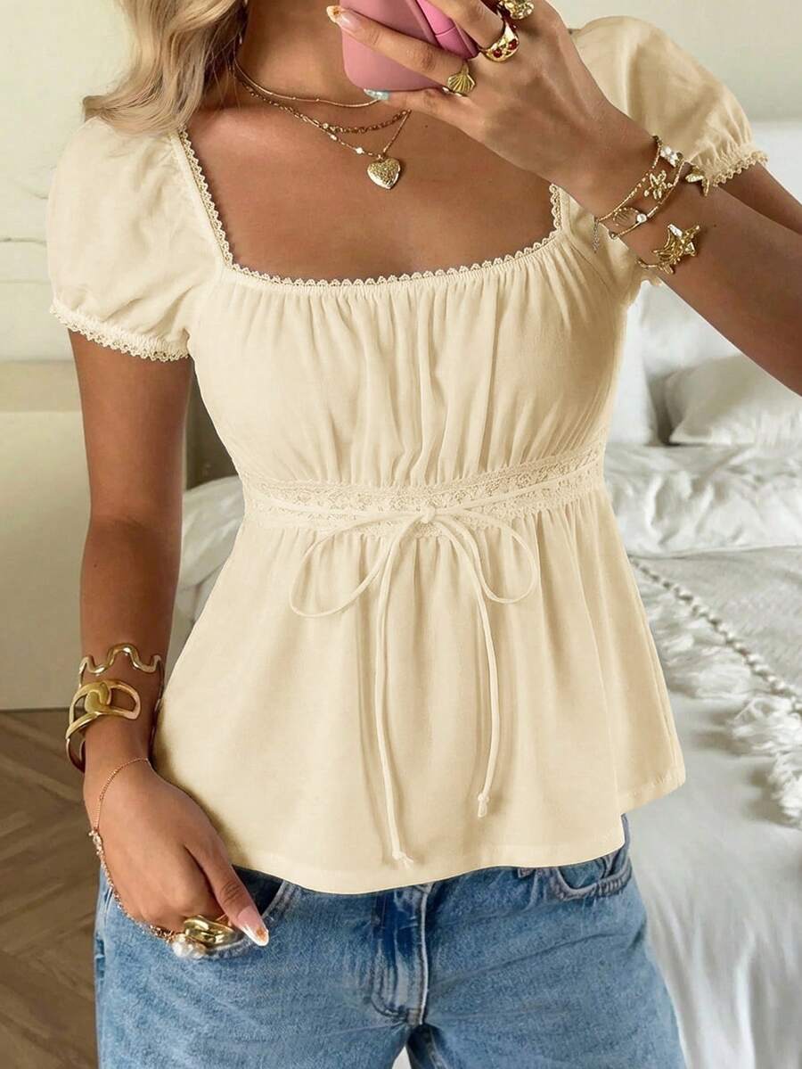Women's black short puff sleeve top featuring a square neckline, ruched bust detail, and flared ruffle hem.