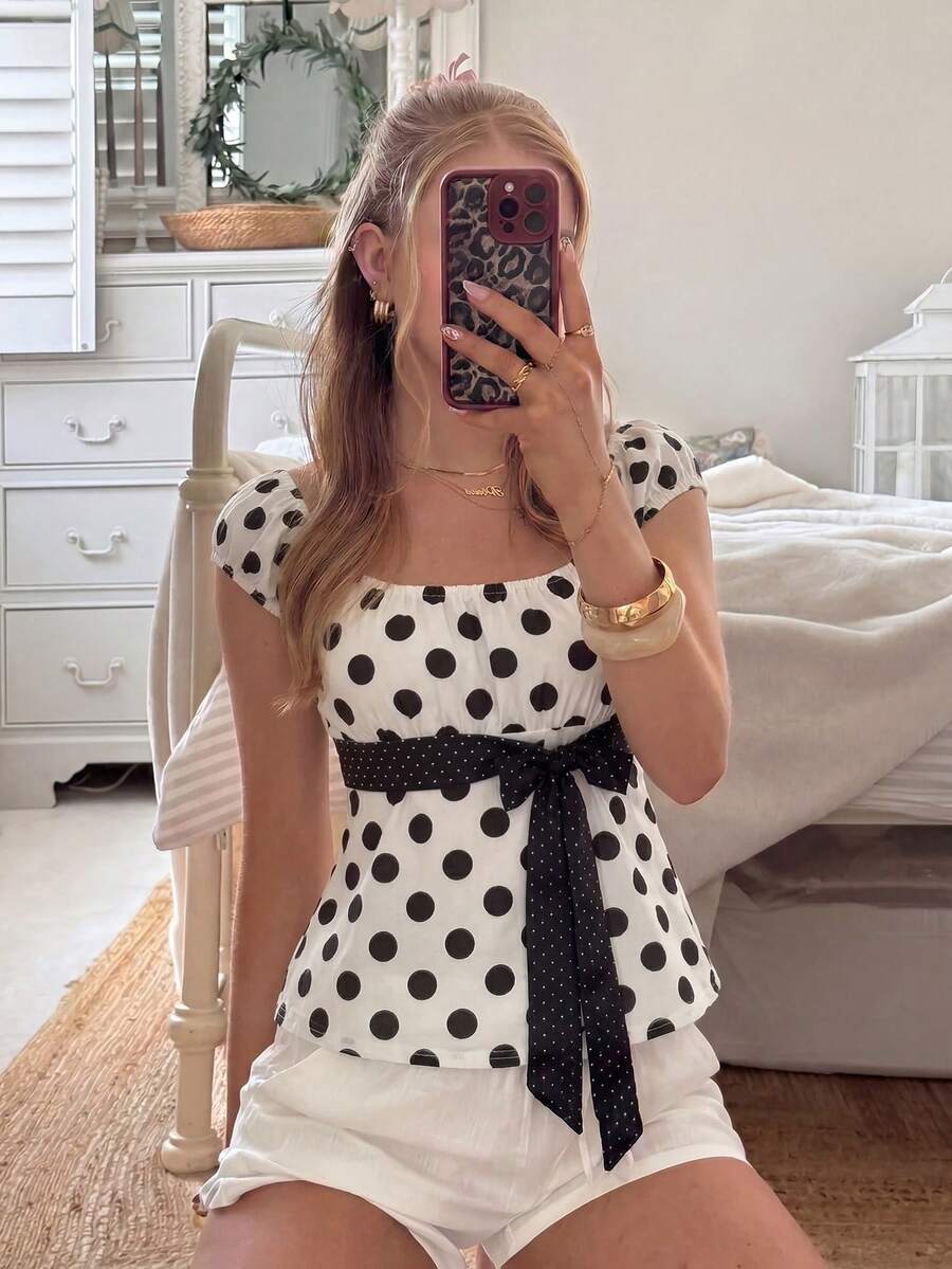 Women's short sleeve square neck polka dot top with ruched detailing, flared hem, and waist tie back.