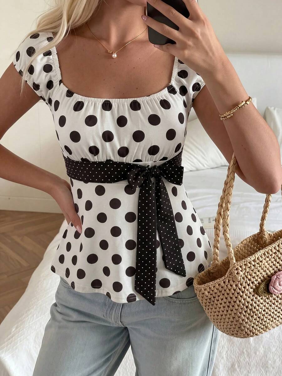 Women's short sleeve square neck polka dot top with ruched detailing, flared hem, and waist tie back.