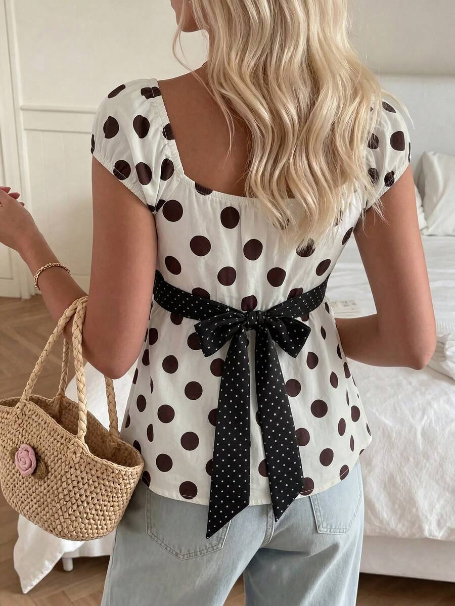 Women's short sleeve square neck polka dot top with ruched detailing, flared hem, and waist tie back.