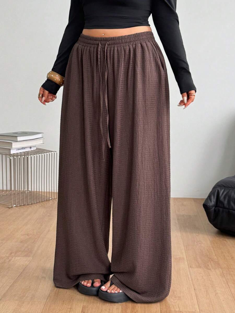 Women's loose straight leg cotton pants featuring a high waist with an adjustable drawstring knot and functional side pockets.