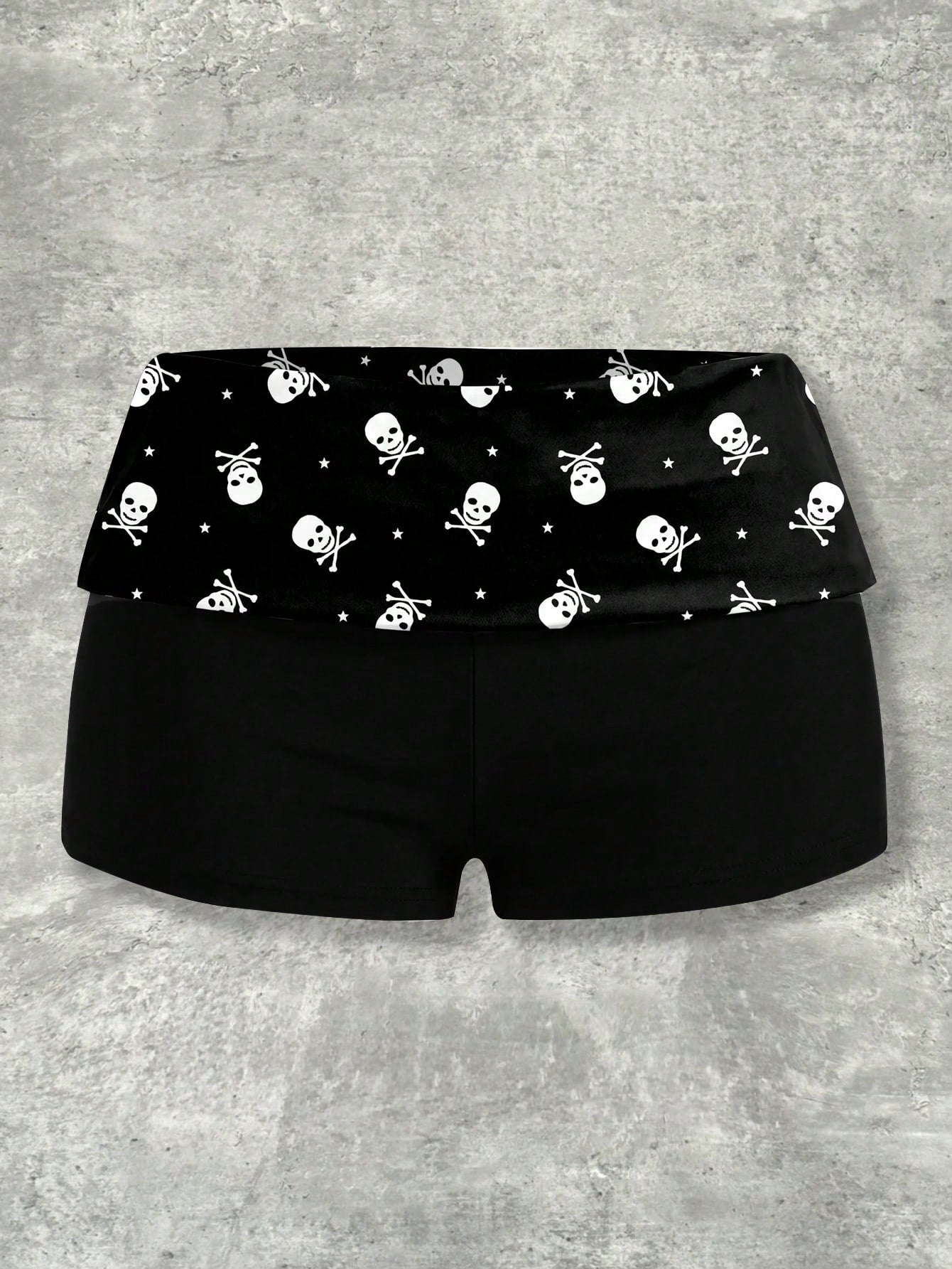 Women's black low waist mini track shorts with contrast polka dot, striped, geometric, and plant-inspired print details, elastic waistband, and skinny fit
