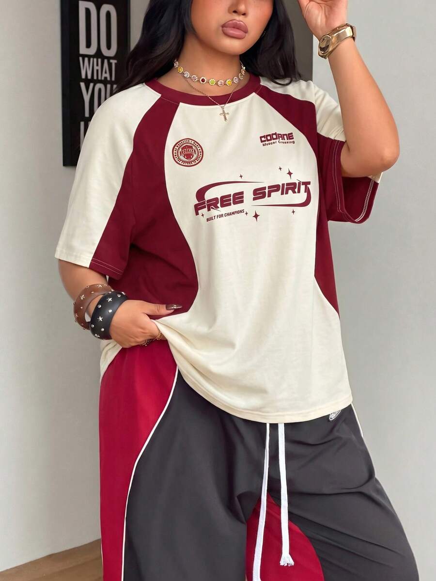 Unisex plus size oversized jersey t-shirt in brown featuring a round neck, short raglan sleeves with contrast binding, and a front letter graphic print.