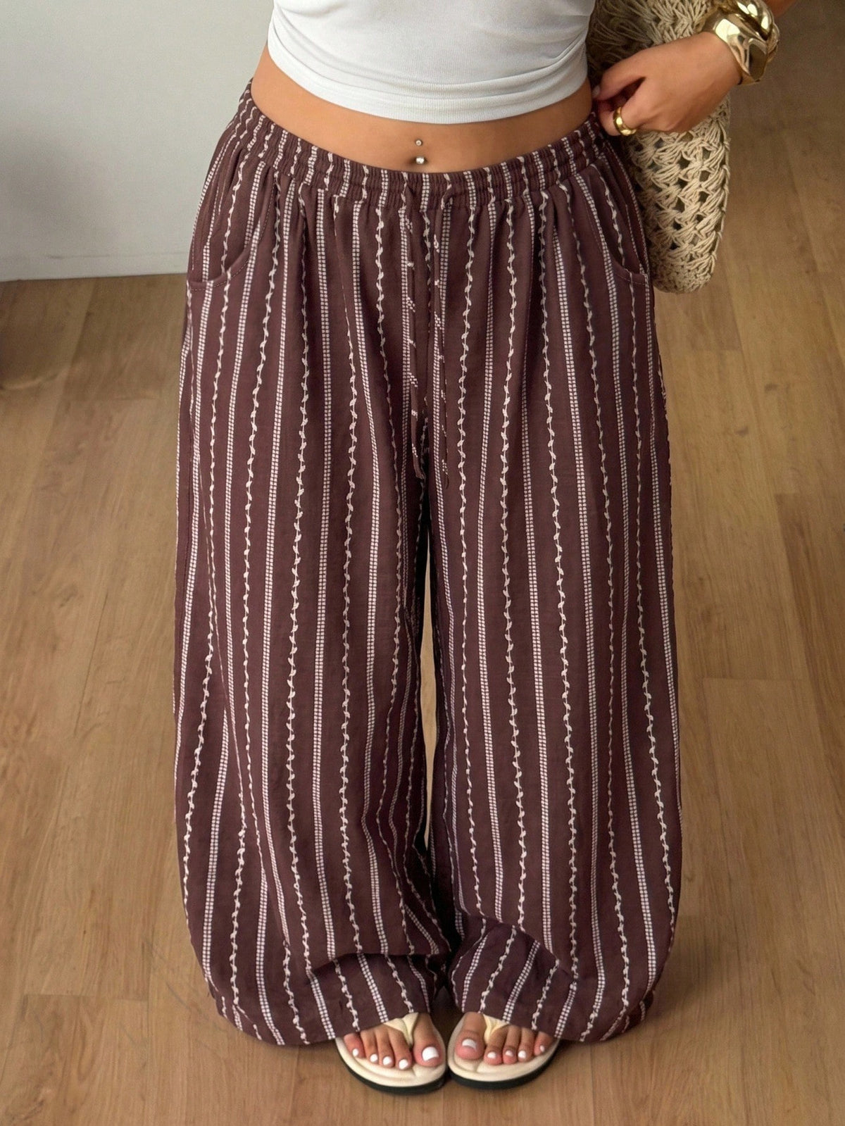 Women's loose straight leg cotton pants featuring a high waist with an adjustable drawstring knot and functional side pockets.