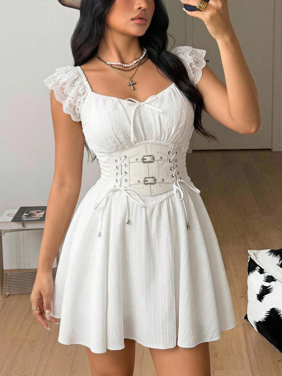 Front view of a white mini dress with sweetheart ruched bust, front lace-up detail, and flounce cap sleeves.