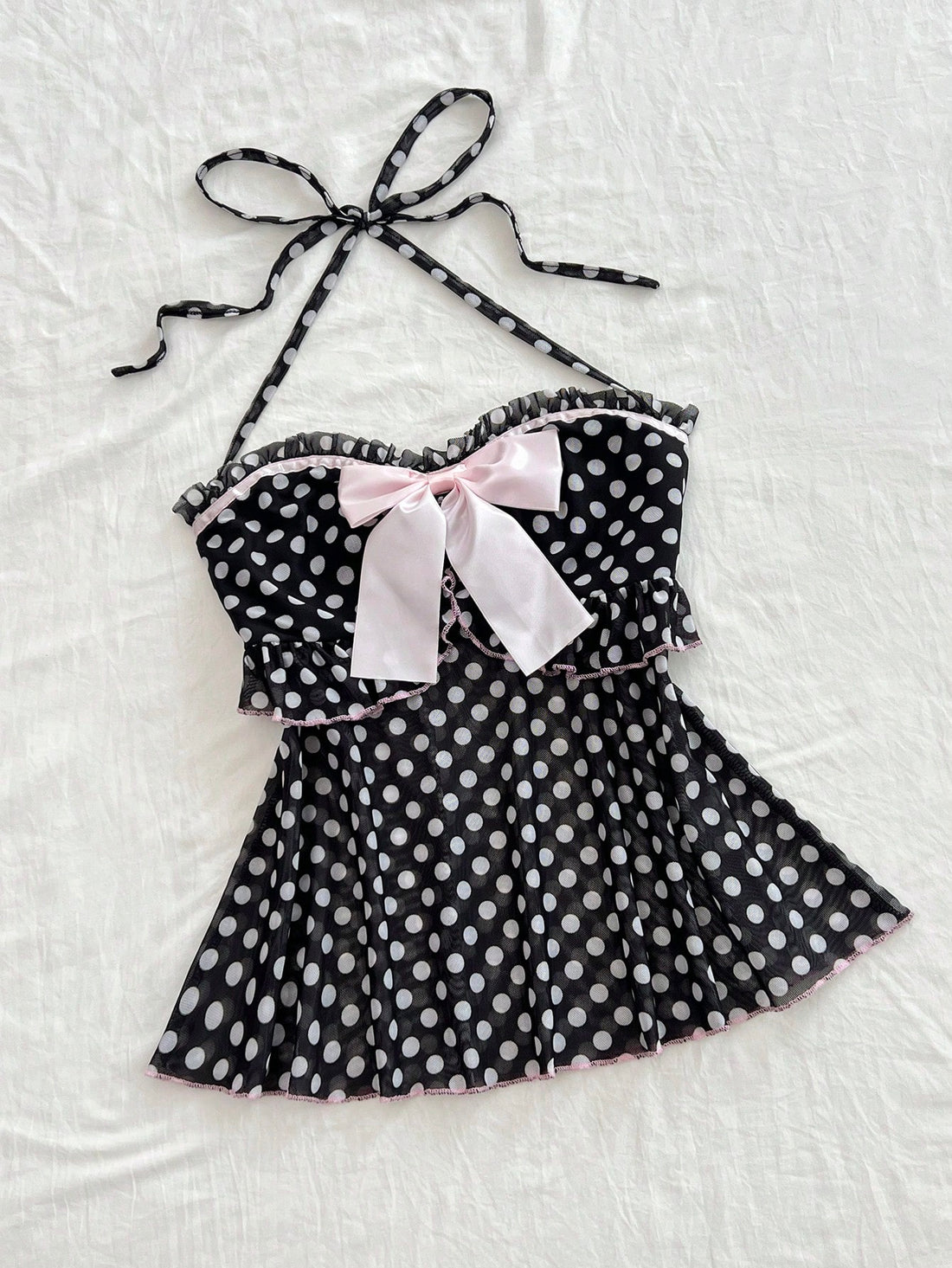Multicolor polka dot print halter neck tank top featuring a 3D bow accent, backless tie straps, and an asymmetrical ruffle hem.
