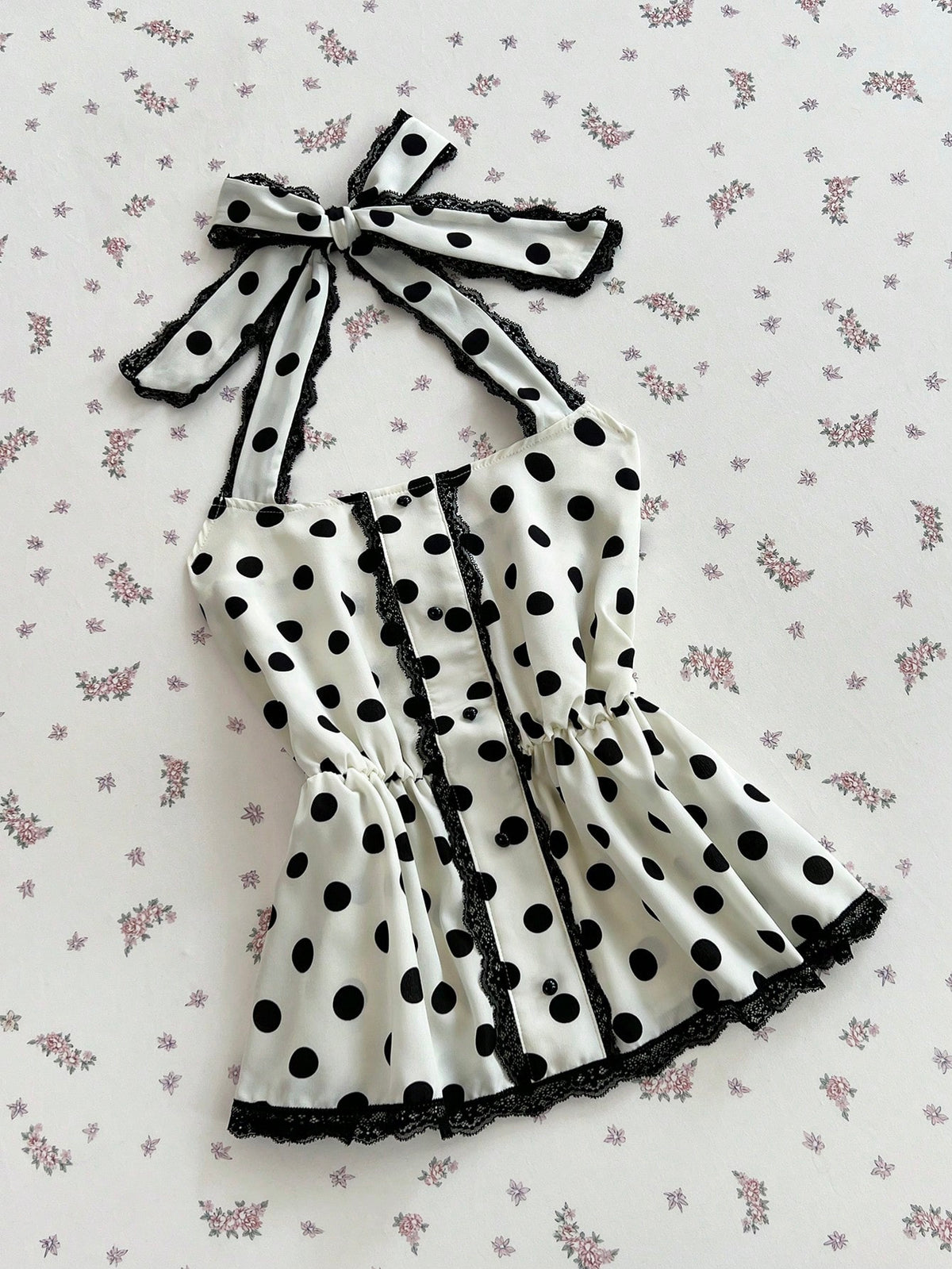 Women's multicolor polka dot halter crop tank top featuring contrast lace, button front details, backless cut, and a flared ruffle hem.