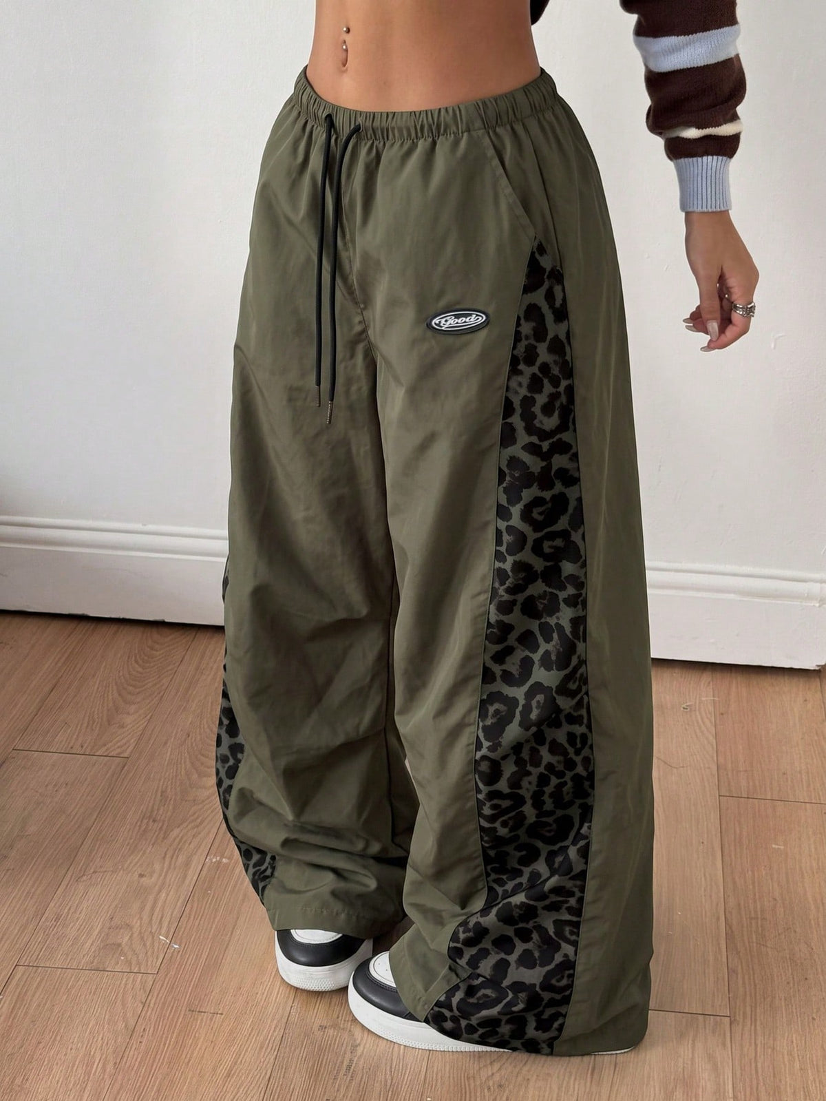 Women's high waist wide leg pants in black featuring leopard print patchwork details and an elastic drawstring waistband.