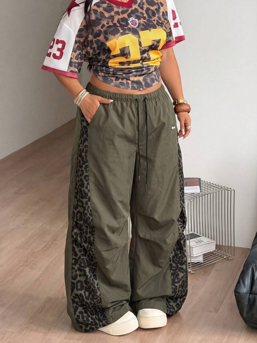 Women's high waist wide leg pants in black featuring leopard print patchwork details and an elastic drawstring waistband.