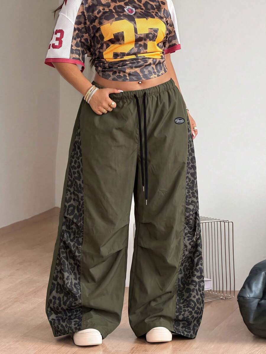 Women's high waist wide leg pants in black featuring leopard print patchwork details and an elastic drawstring waistband.