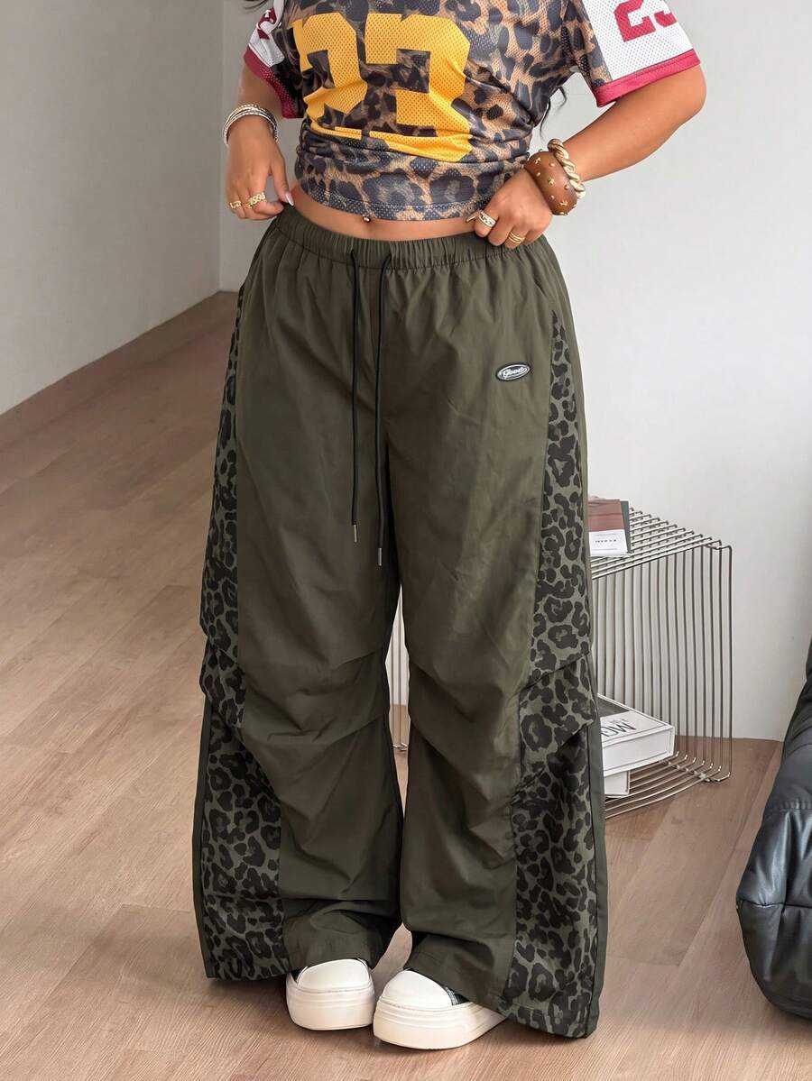 Women's high waist wide leg pants in black featuring leopard print patchwork details and an elastic drawstring waistband.