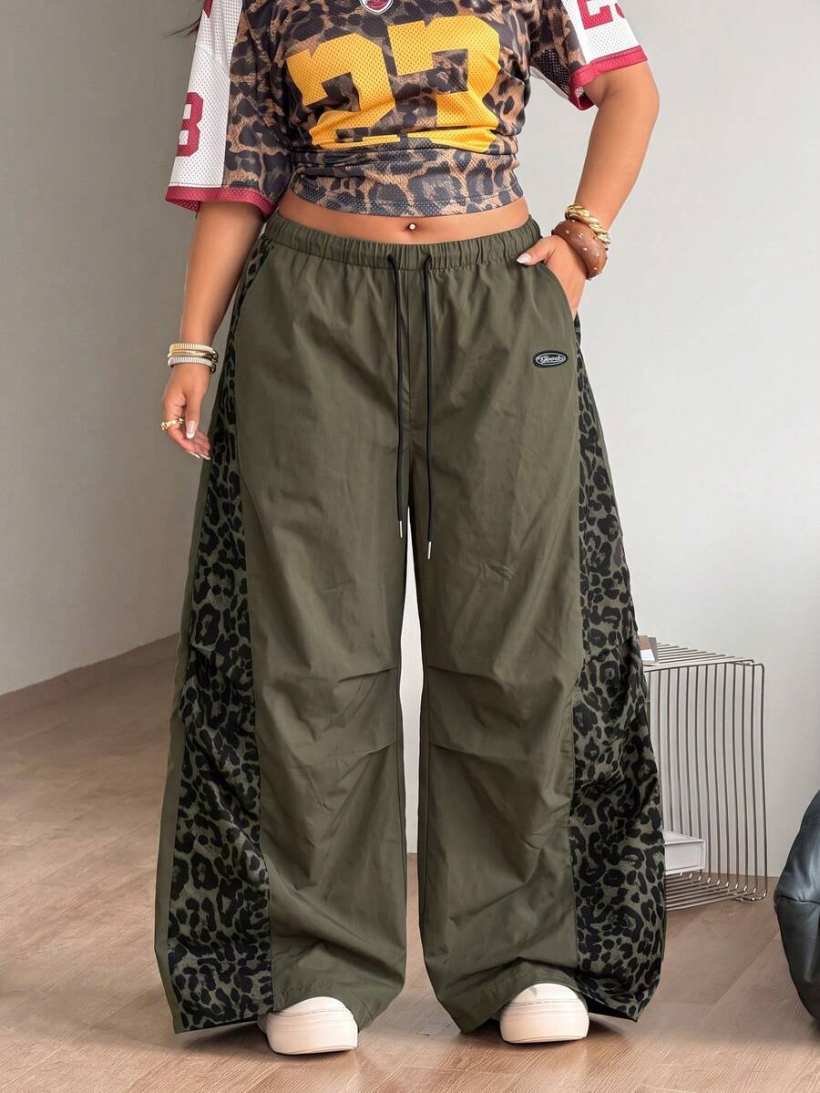 Women's high waist wide leg pants in black featuring leopard print patchwork details and an elastic drawstring waistband.