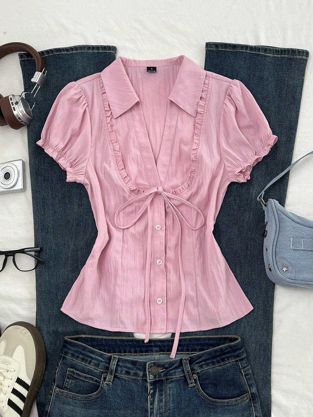 Pink short sleeve V-neck blouse featuring flounce sleeves, lace-up bow tie detail, ruffle accents, and button front closures.