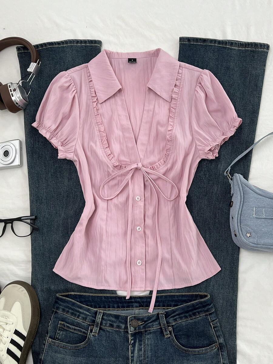 Pink short sleeve V-neck blouse featuring flounce sleeves, lace-up bow tie detail, ruffle accents, and button front closures.