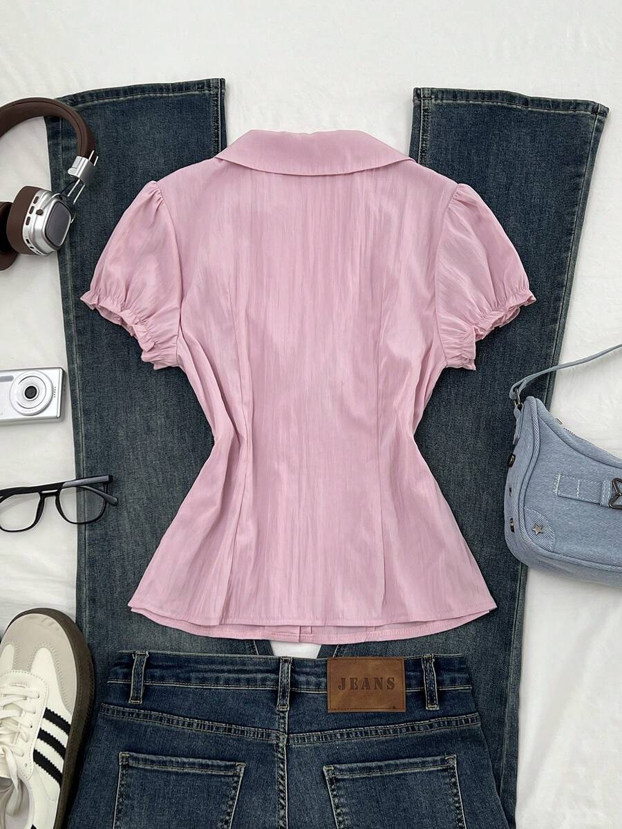Pink short sleeve V-neck blouse featuring flounce sleeves, lace-up bow tie detail, ruffle accents, and button front closures.