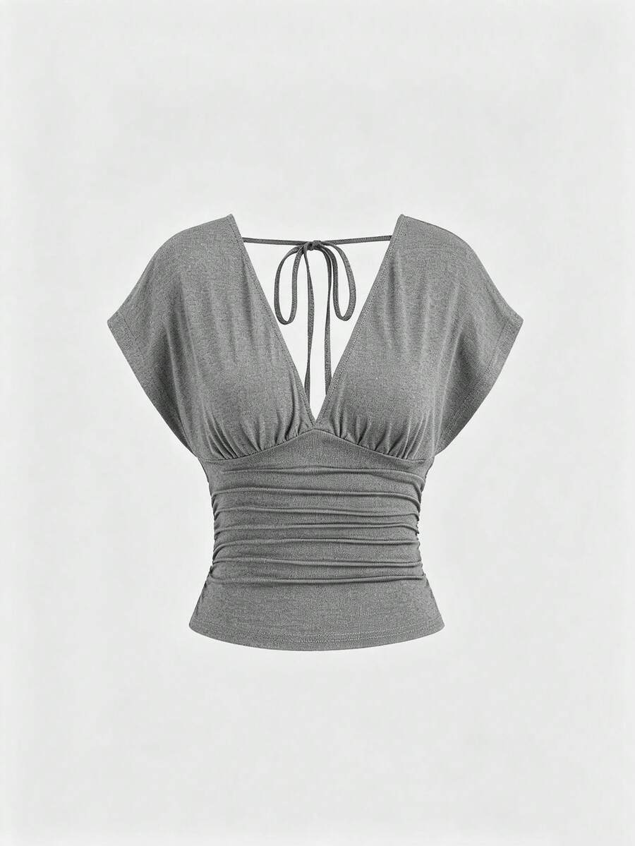 Women's black knitted t-shirt featuring a reversible deep v-neckline, batwing cap sleeves, ruched detailing, and a slim fit waist.