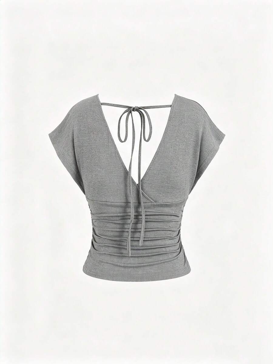 Women's black knitted t-shirt featuring a reversible deep v-neckline, batwing cap sleeves, ruched detailing, and a slim fit waist.