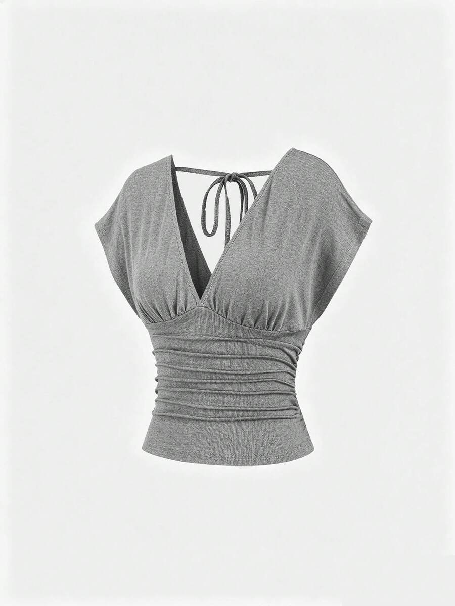 Women's black knitted t-shirt featuring a reversible deep v-neckline, batwing cap sleeves, ruched detailing, and a slim fit waist.