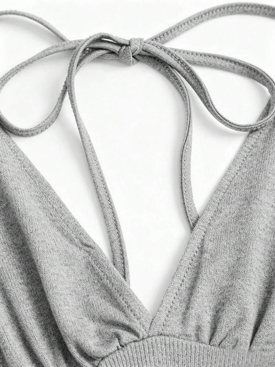 Women's black knitted t-shirt featuring a reversible deep v-neckline, batwing cap sleeves, ruched detailing, and a slim fit waist.