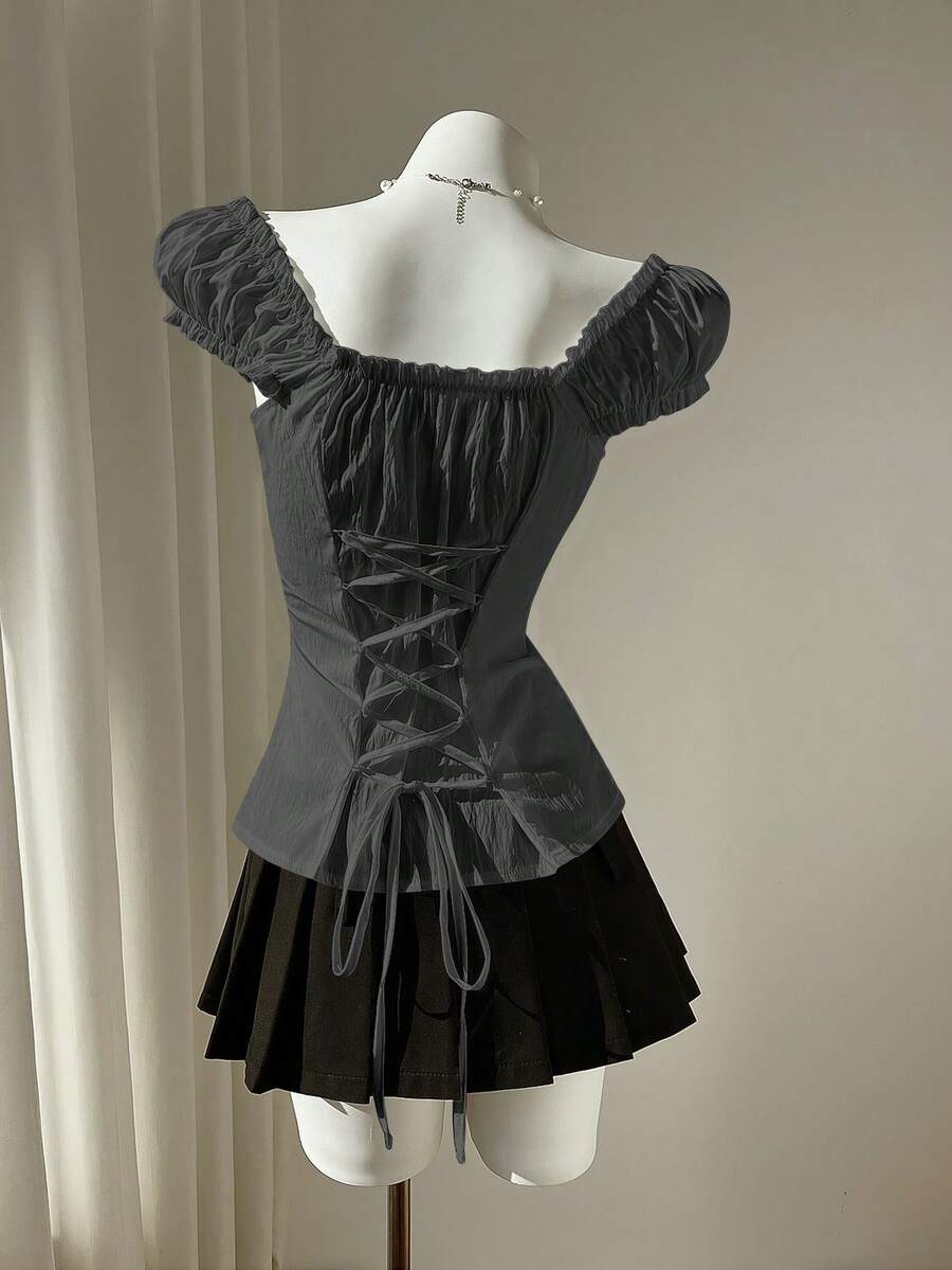 Women's black off-shoulder cap sleeve blouse with ruffled detailing and a tie-back design.
