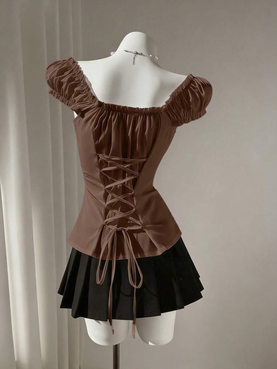 Women's black off-shoulder cap sleeve blouse with ruffled detailing and a tie-back design.
