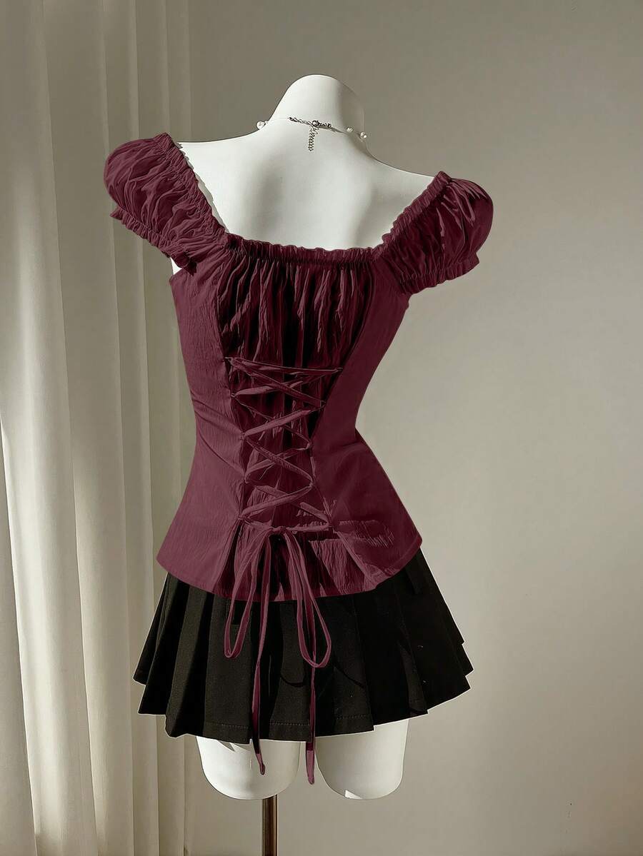 Women's black off-shoulder cap sleeve blouse with ruffled detailing and a tie-back design.