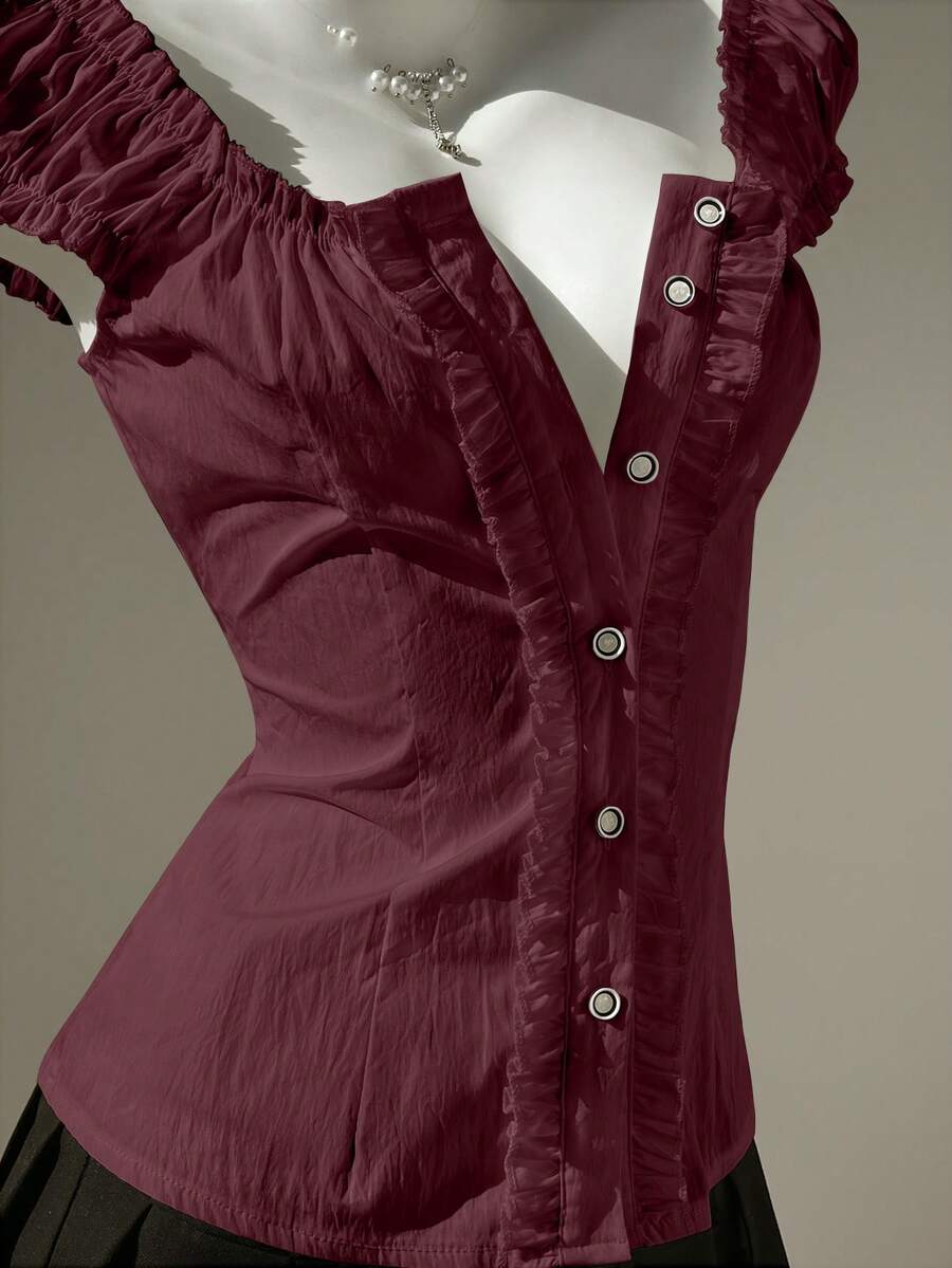 Women's black off-shoulder cap sleeve blouse with ruffled detailing and a tie-back design.