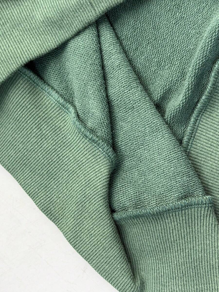 Women's sage green asymmetrical shoulder sweatshirt with button eyelet detail, drop shoulder long sleeves, and a loose casual fit.