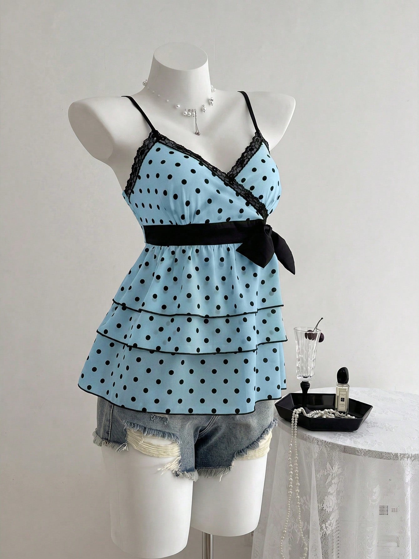 Women's polka dot camisole top with contrast lace trim, tank vest neckline, slim fit, and flared ruffle hem.