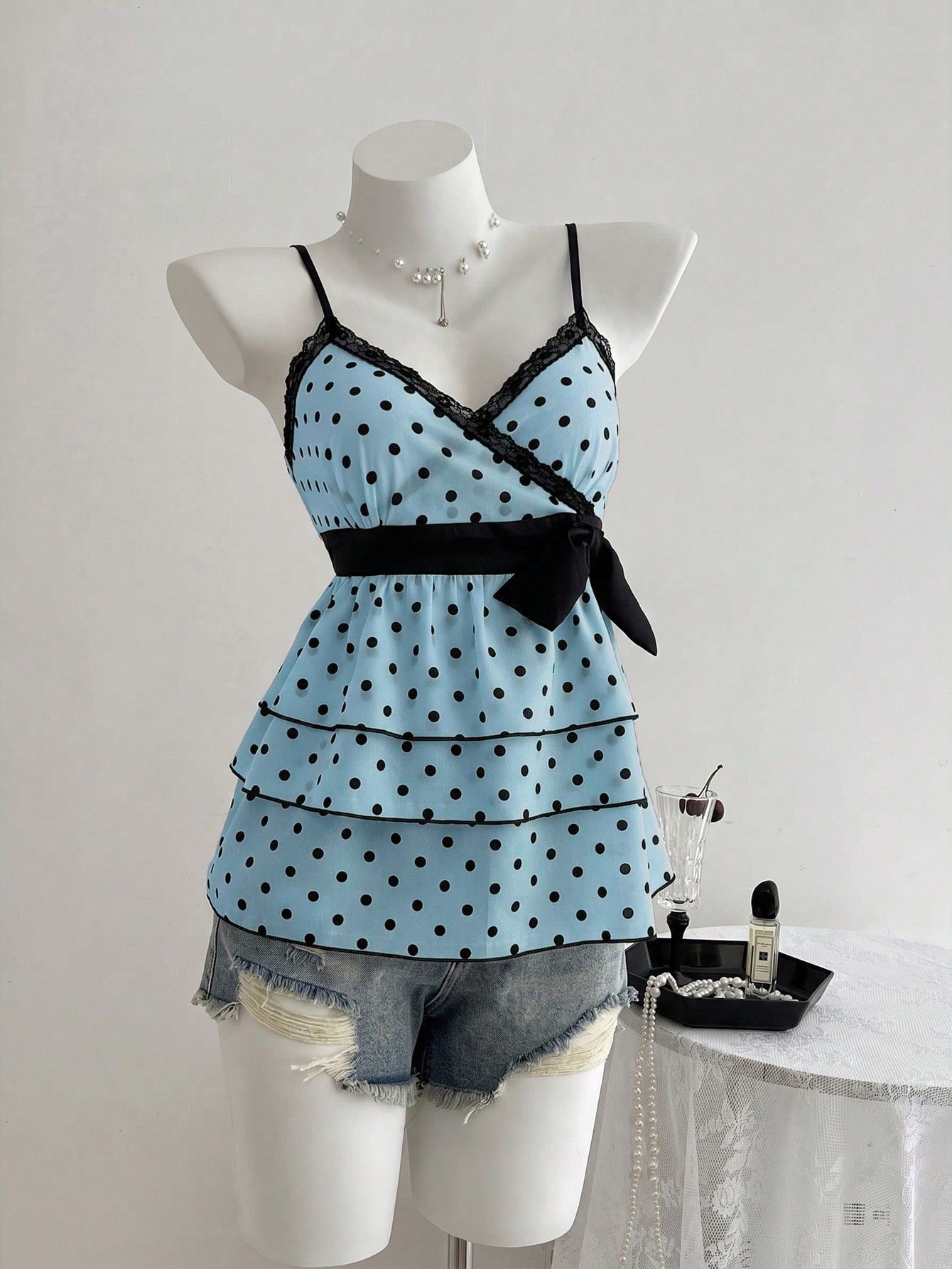 Women's polka dot camisole top with contrast lace trim, tank vest neckline, slim fit, and flared ruffle hem.