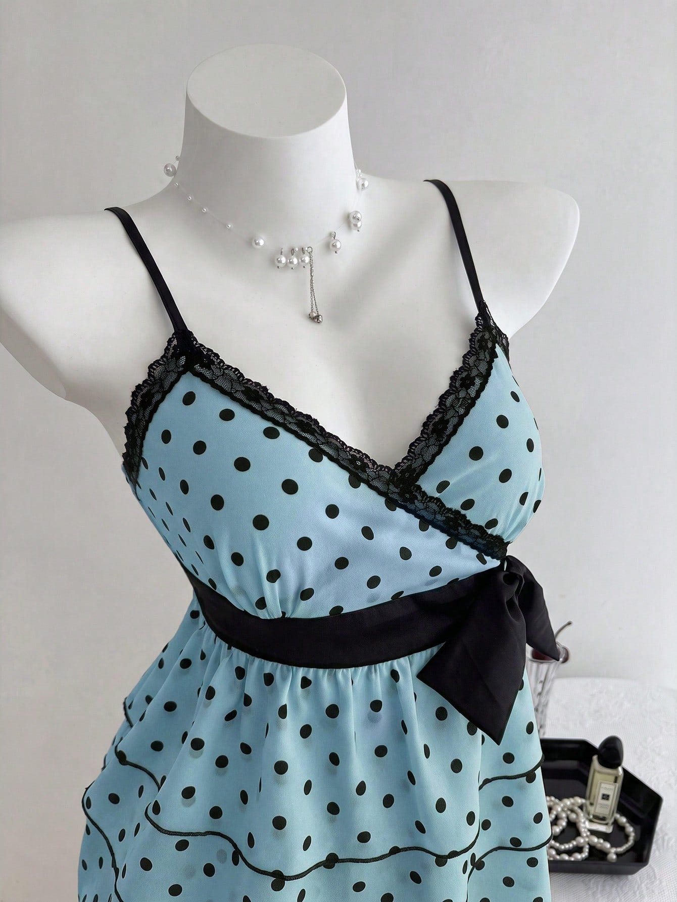 Women's polka dot camisole top with contrast lace trim, tank vest neckline, slim fit, and flared ruffle hem.