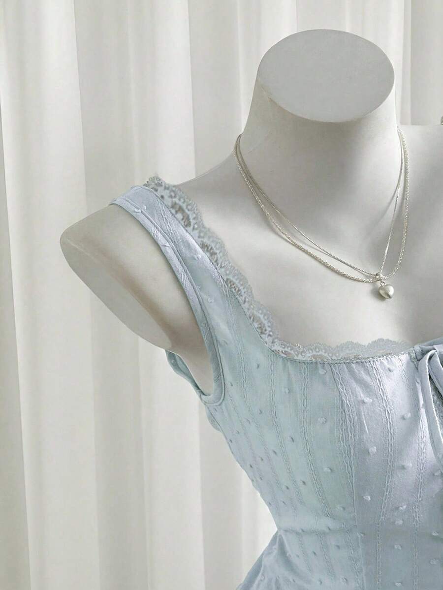 Women's 100% cotton sleeveless camisole top featuring a square neckline, wide straps, lace-up knot detail, and an asymmetrical hem.
