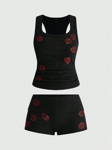 Punk-inspired two-piece set with a fitted scoop neck slogan tank top featuring cross and rhinestone details paired with ultra low waist mini shorts.