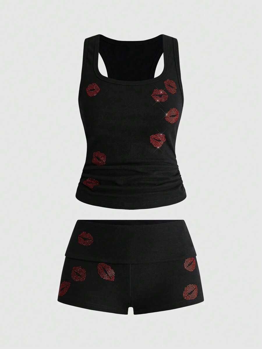 Punk-inspired two-piece set with a fitted scoop neck slogan tank top featuring cross and rhinestone details paired with ultra low waist mini shorts.