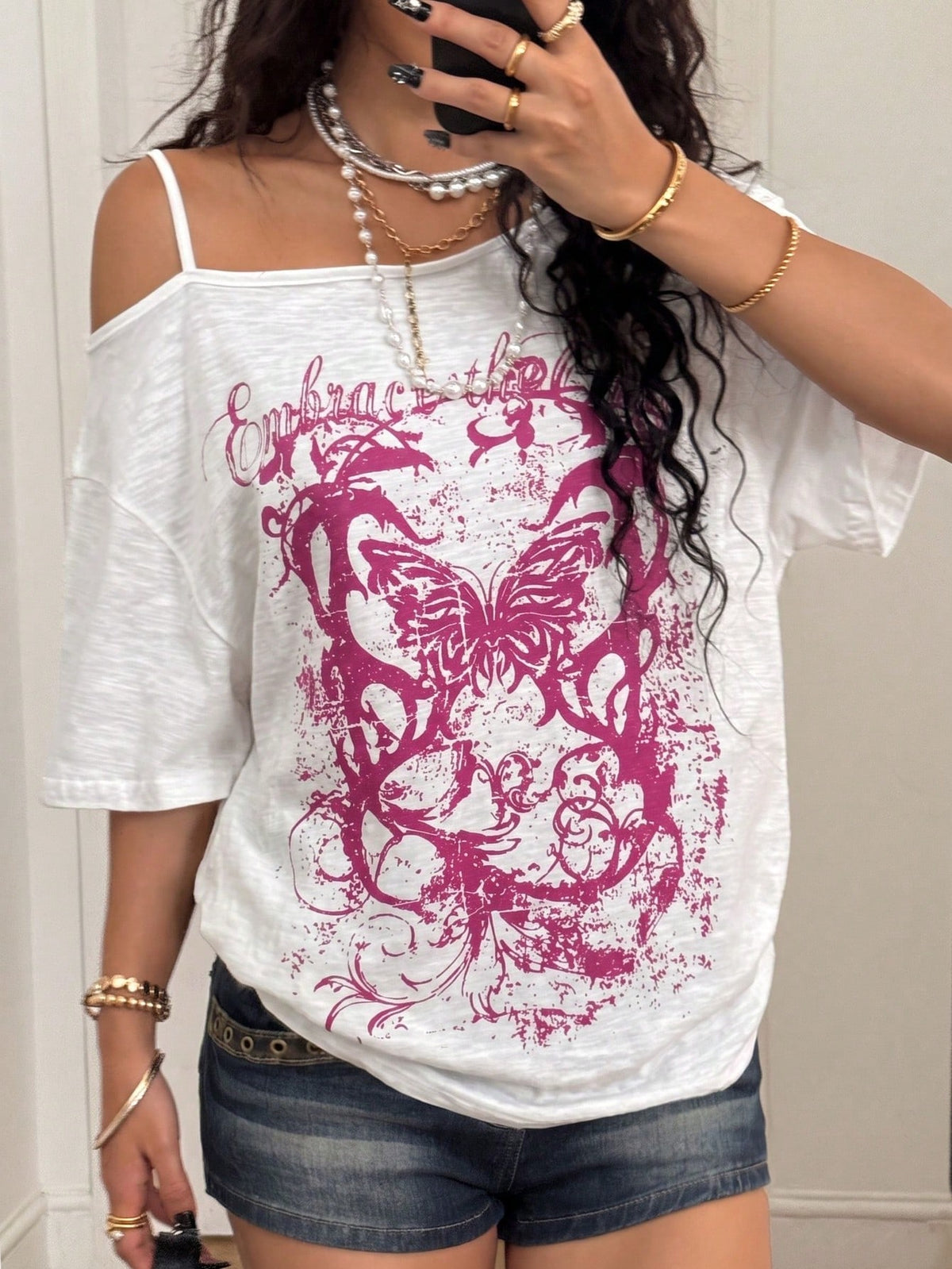 Women's loose-fit black cotton oversized t-shirt featuring an asymmetrical cold shoulder cutout neckline and short drop-shoulder sleeves.