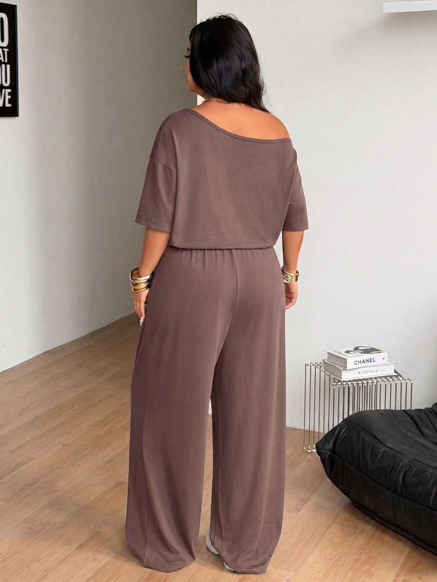 Plus size women's wide leg jumpsuit in dark grey featuring an asymmetrical neckline, short batwing sleeves, and a drawstring high waist with side pockets.