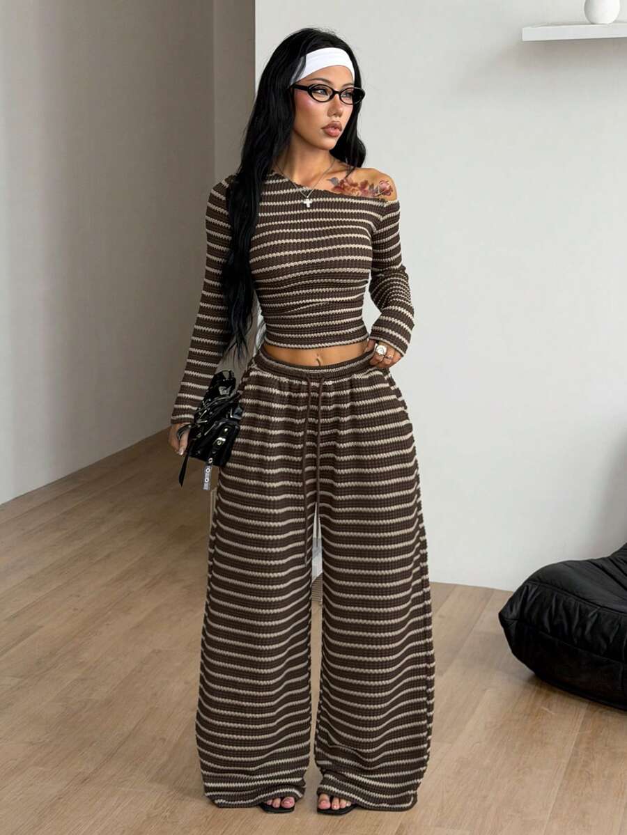 Women's two-piece striped knit tracksuit set featuring a brown asymmetrical neckline long sleeve crop top and matching high-waisted wide leg sweatpants.