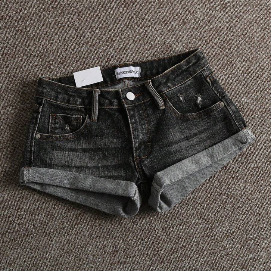 Women's low-waist shorts with ripped hem, asymmetrical detail, straight-leg cut, and pockets.