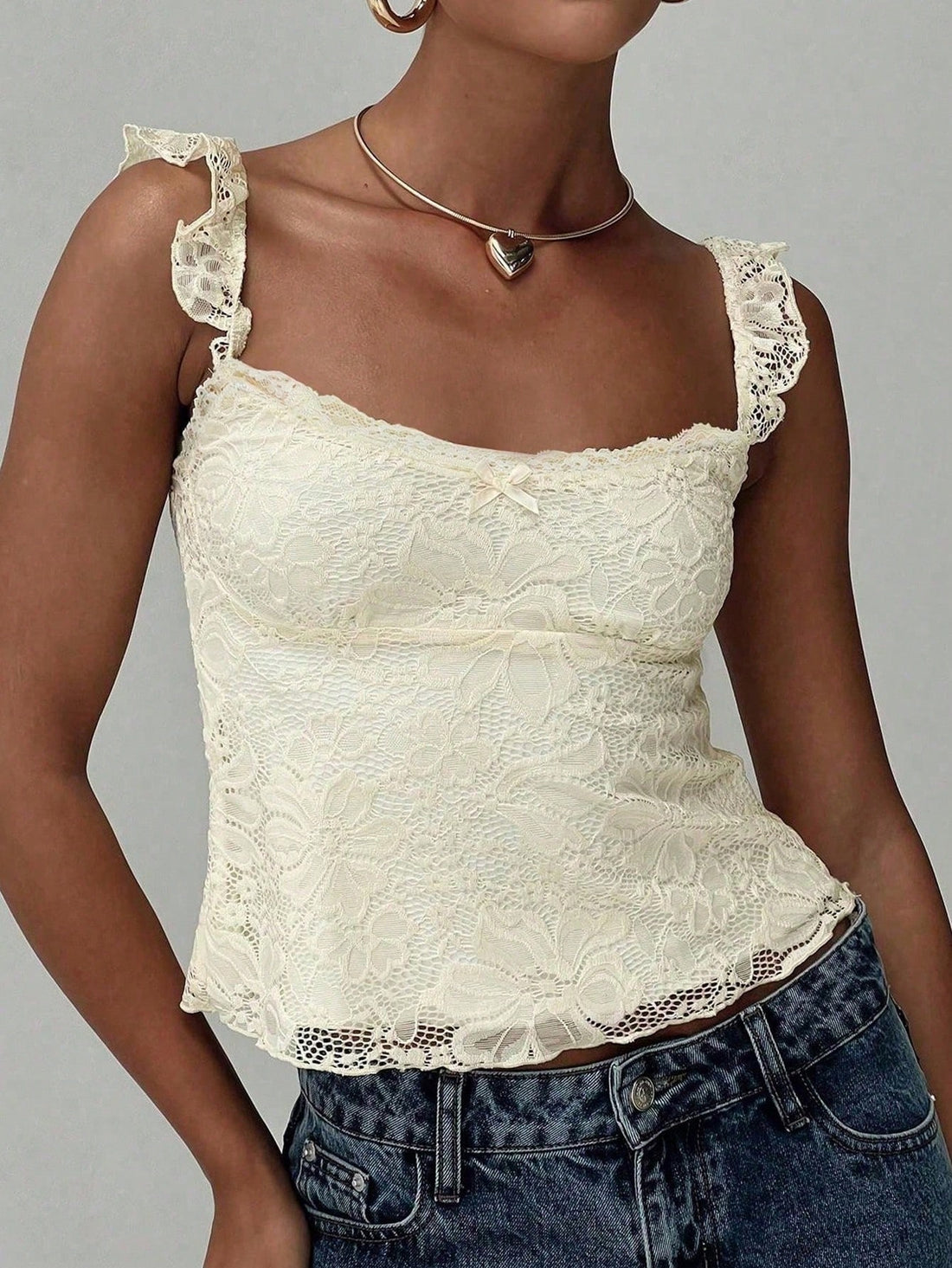 Sleeveless cami tank top featuring contrast lace patchwork design, ruffle spaghetti straps, and bow decor.